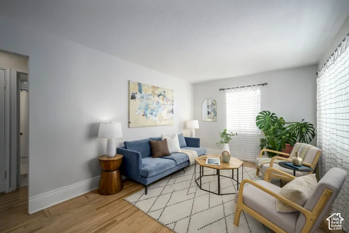 Light wood-finish flooring with white baseboards, bright white walls, and a window with blinds
