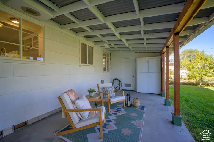 Covered patio with exposed wood beams and a corrugated metal ceiling