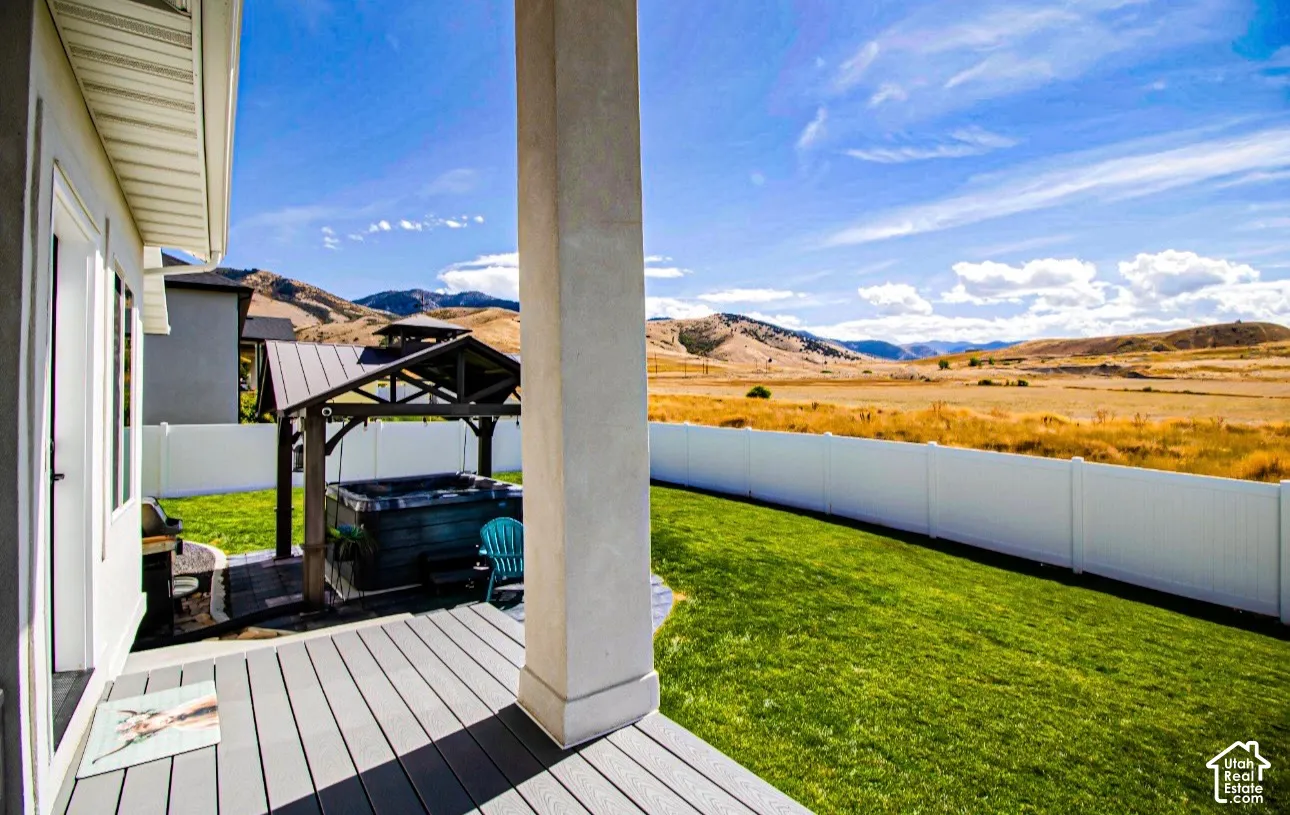 Expansive backyard featuring a manicured lawn, a privacy fence, and a gazebo-covered hot tub