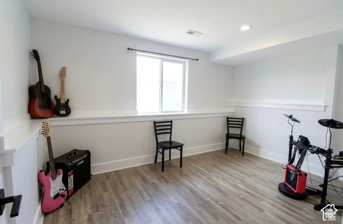 Recessed lighting, wood-finish flooring, white trim, and a window with a dark curtain rod