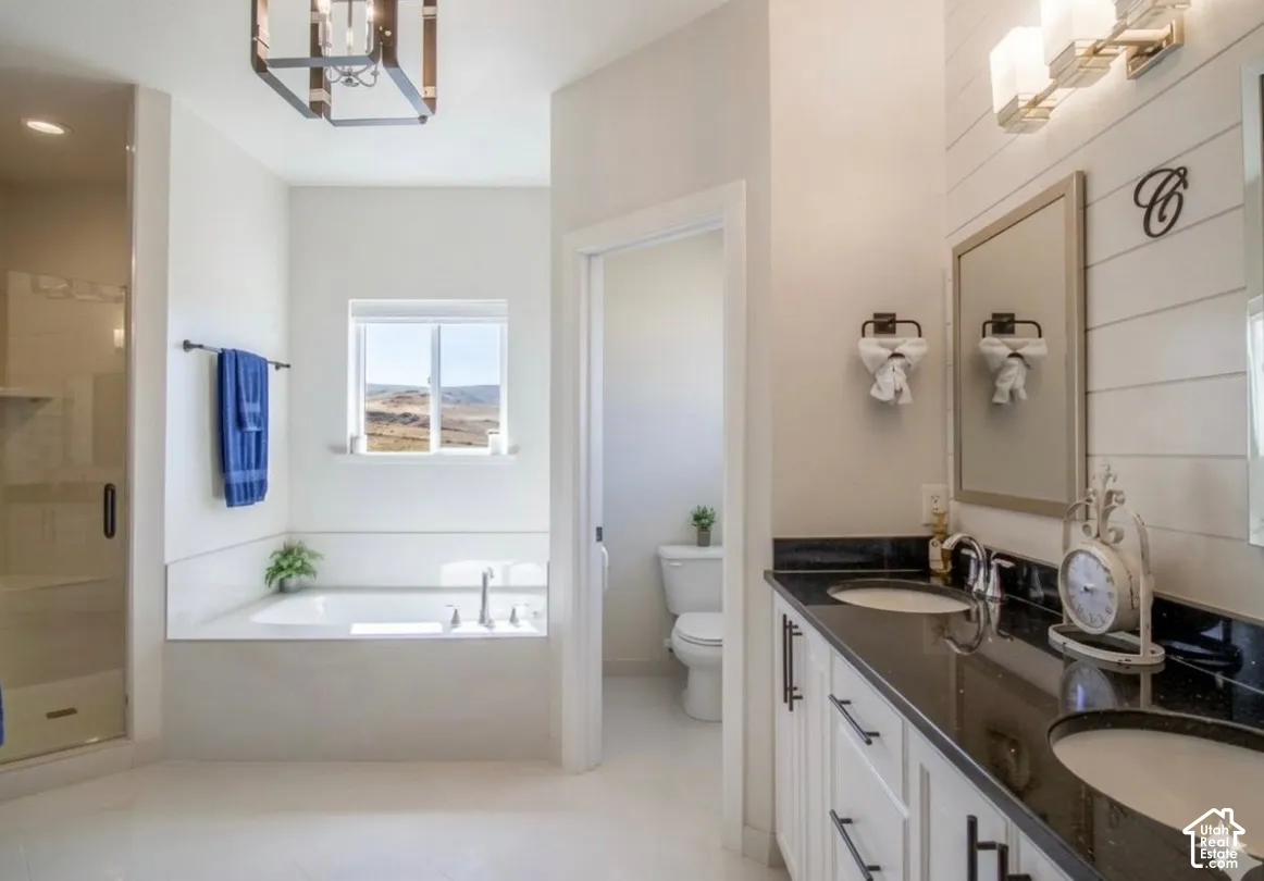 Dual vanity with dark countertops, white cabinetry, and wall-mounted lighting