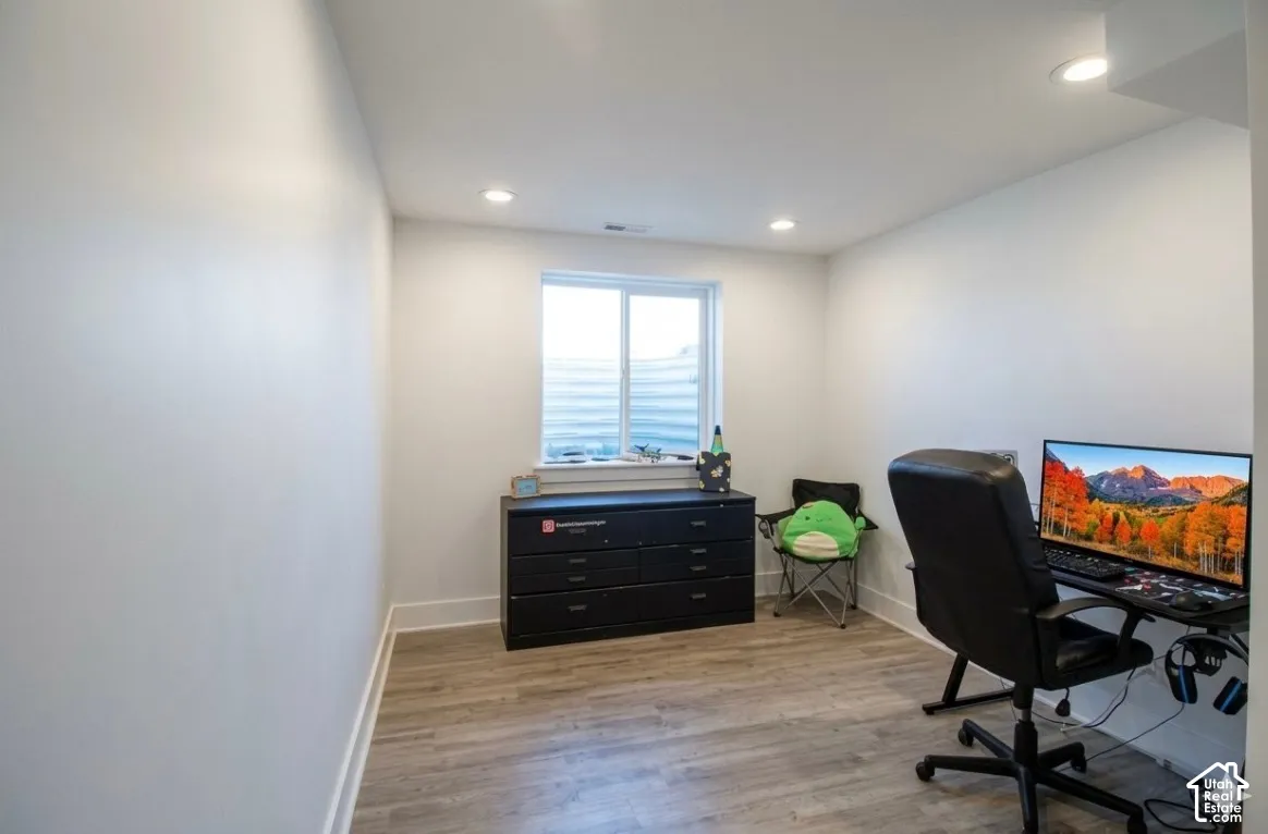 Recessed lighting, wood-finish flooring, and a window with horizontal blinds