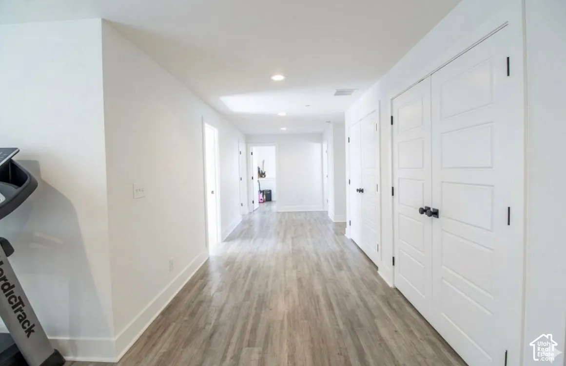 Wood-finish flooring, recessed lighting, and multiple white paneled doors with black hardware