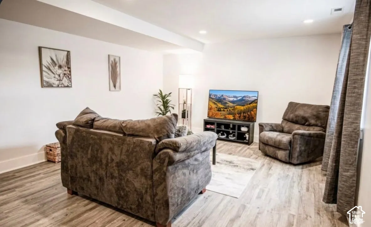 Recessed lighting illuminates the white walls and wood-finish flooring