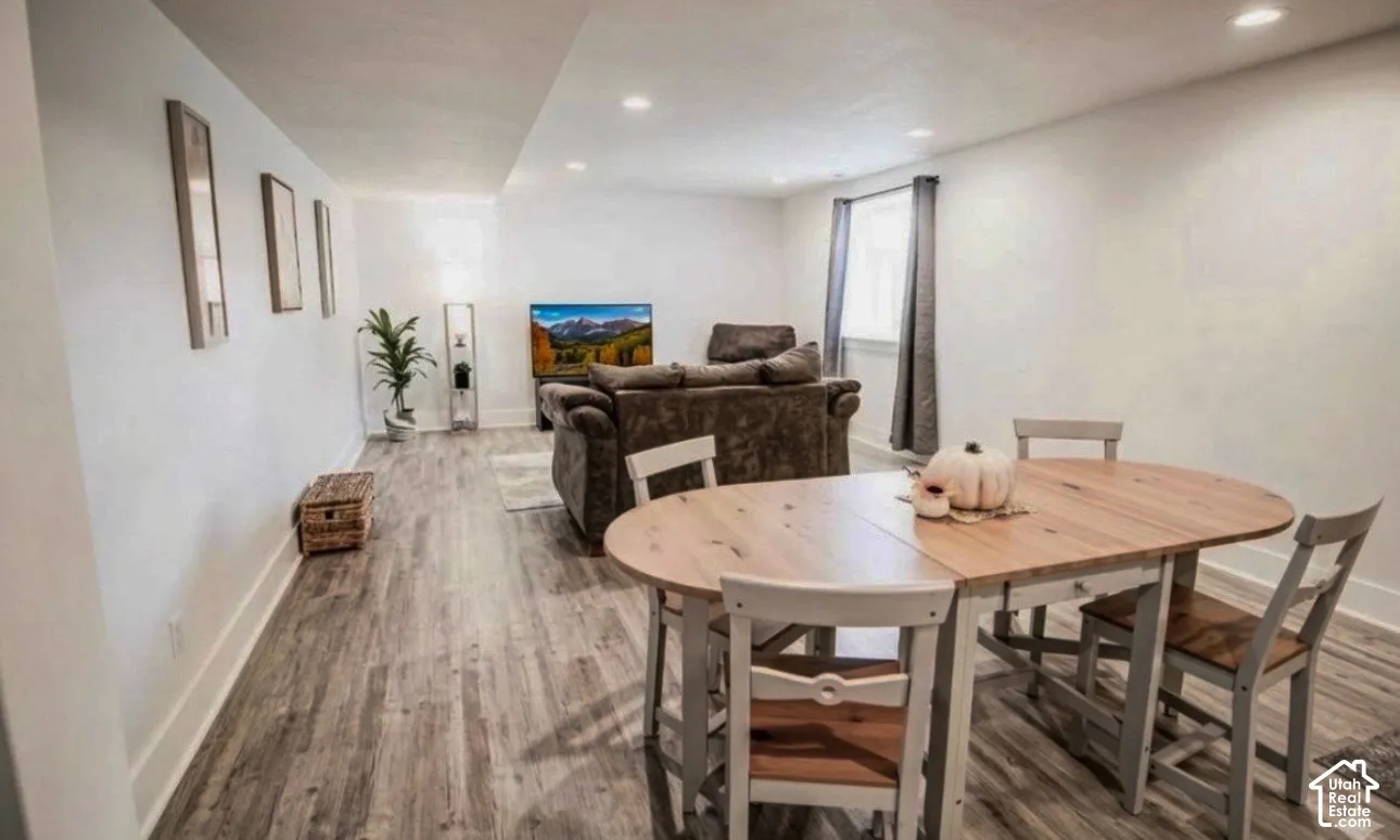 Recessed lighting, wood-finish flooring, white walls, and a window with curtains