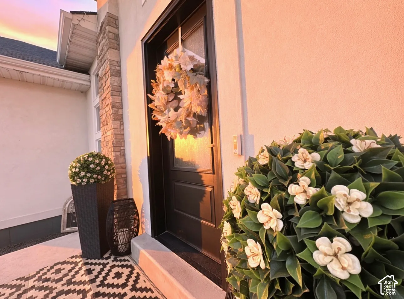 Stucco exterior with stone accents, dark entry door with frosted glass, and a concrete porch