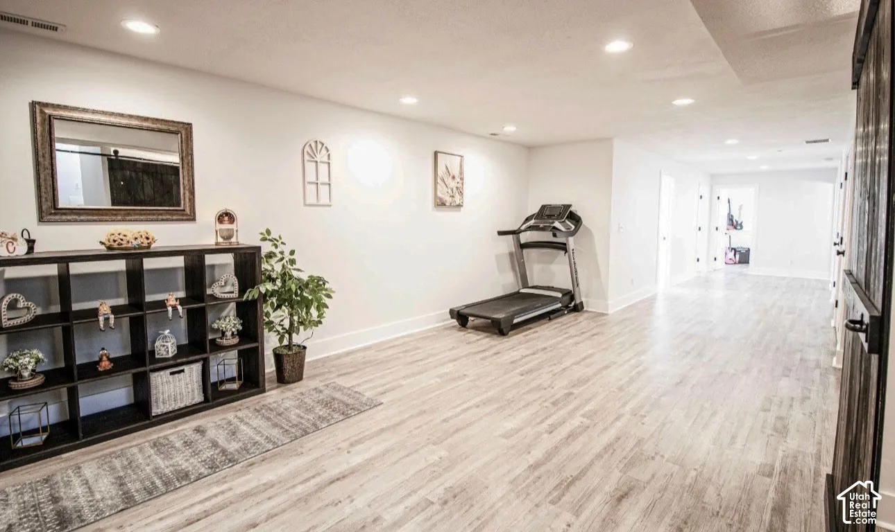 Spacious room with recessed lighting, wood-finish flooring, white walls, and white trim