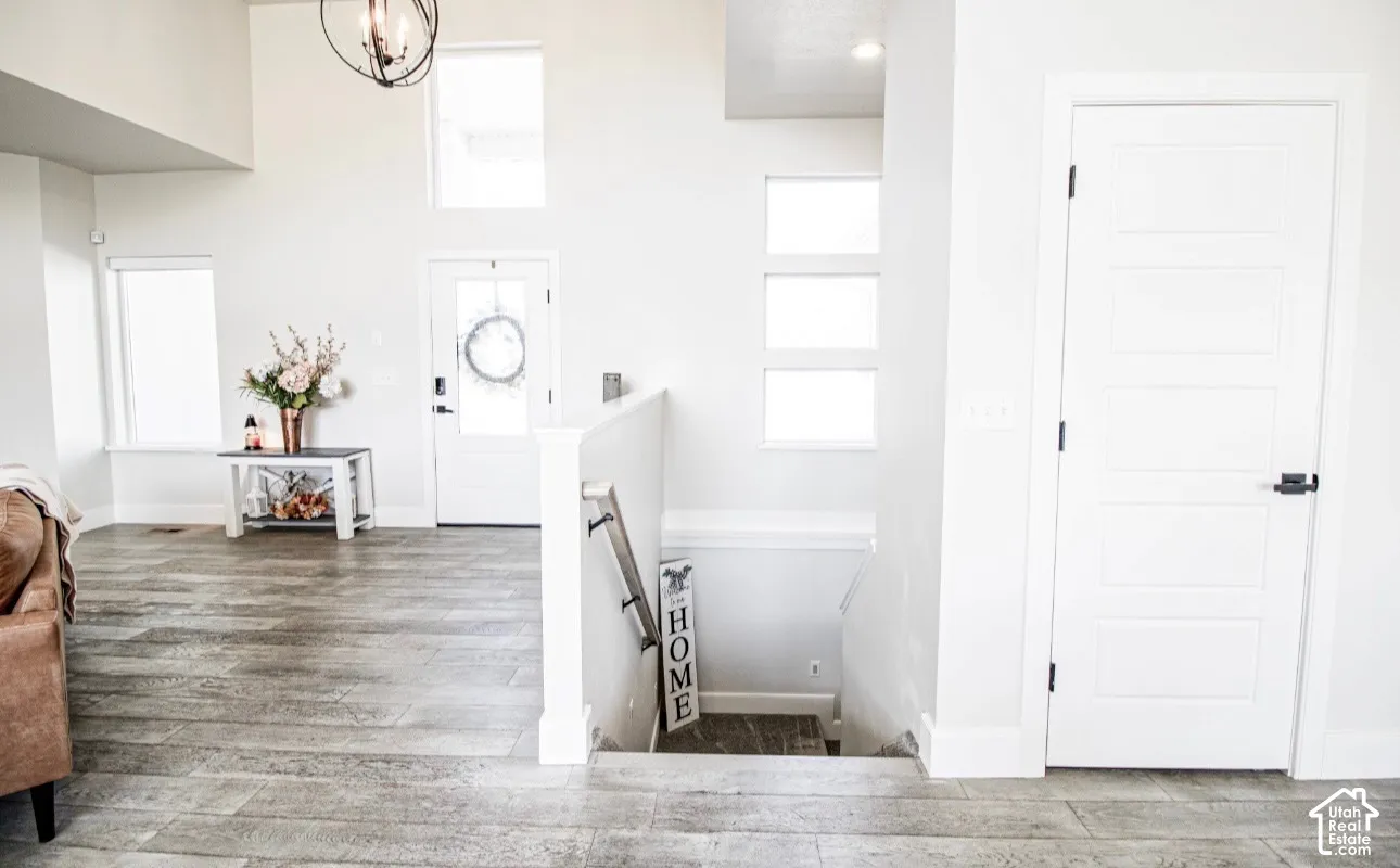 High ceilings, wood-finish flooring, white walls, transom windows, and an orb chandelier
