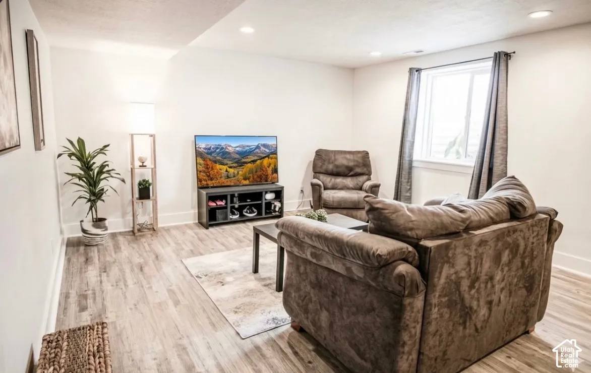 Recessed lighting, wood-finish flooring, white walls, and a casement window