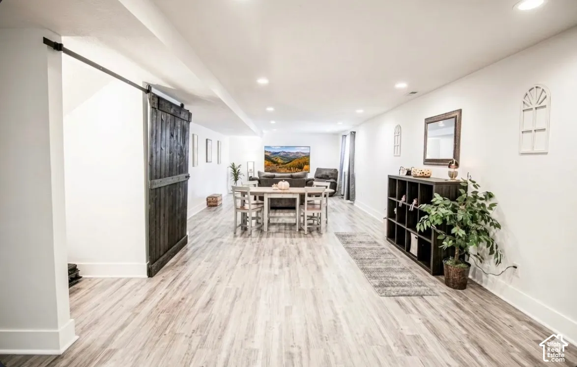 Spacious open-concept interior with wood-finish flooring, recessed lighting, and a dark wood barn door