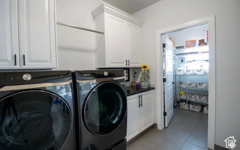 Laundry area with white cabinetry, a black countertop, and tile flooring