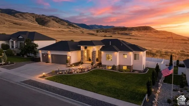 Contemporary exterior with stone accents, a landscaped lawn, and a paved driveway