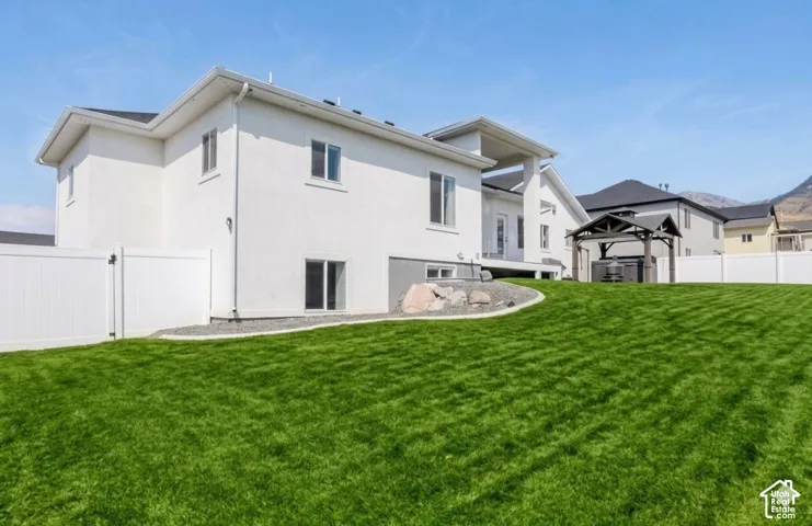 Expansive green lawn with a white vinyl fence, gravel landscaping, and a covered gazebo