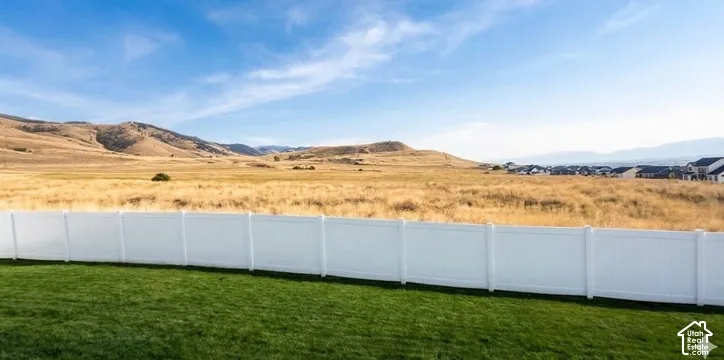 Expansive green lawn with a white privacy fence