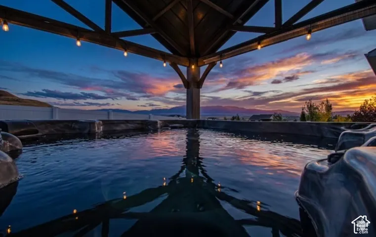 Outdoor spa with a slatted gazebo featuring string lighting and a surrounding privacy fence