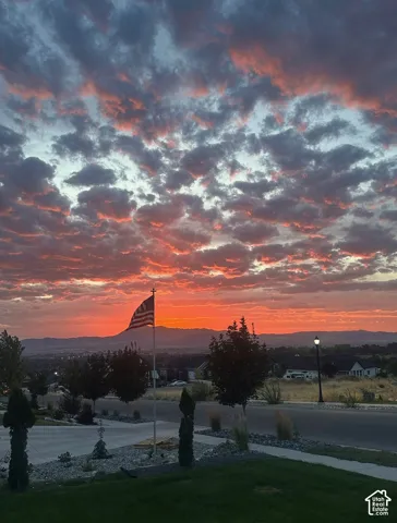 Expansive sky with prominent cloud formations, distant mountain range, and a visible street lamp