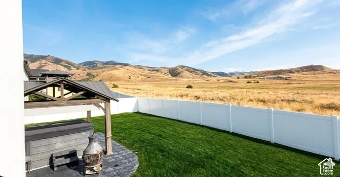Expansive backyard featuring a manicured lawn, white privacy fencing, and a built-in pergola