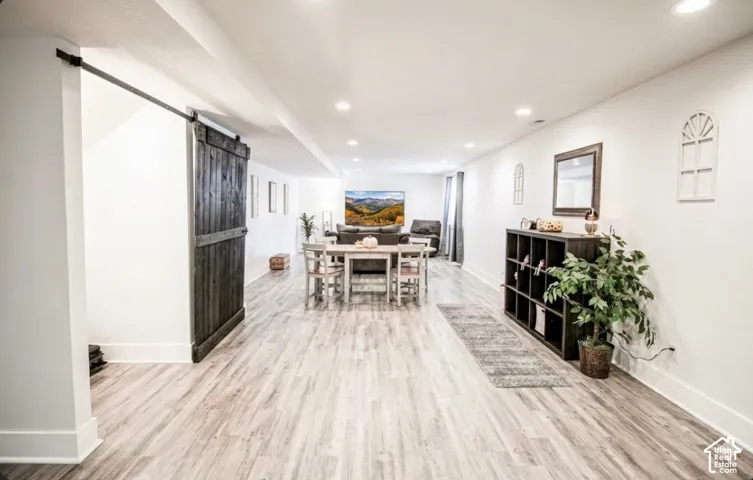 Spacious open-concept interior with wood-finish flooring, recessed lighting, and a dark wood barn door