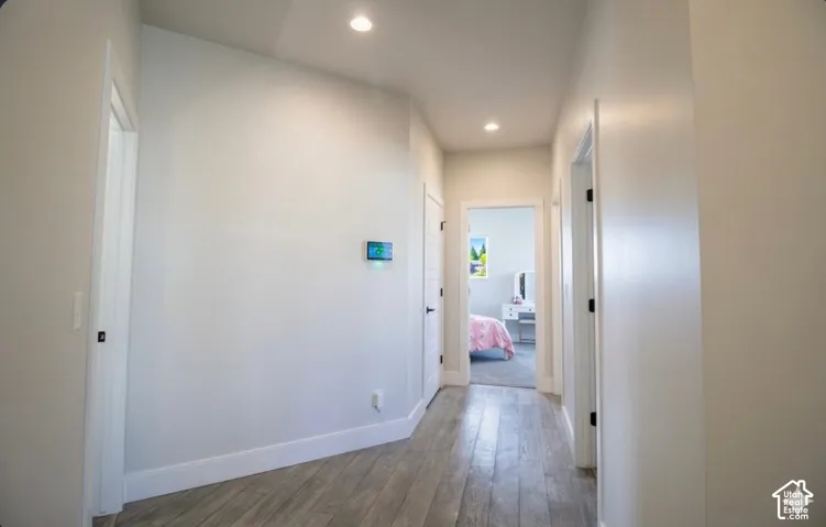 Hallway featuring wood-finish flooring, recessed lighting, white walls, and white trim