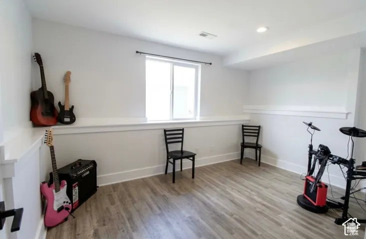 Recessed lighting, wood-finish flooring, white trim, and a window with a dark curtain rod