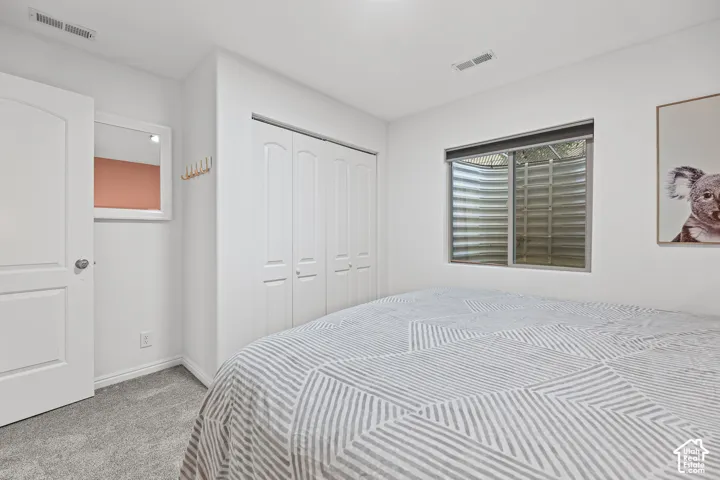 White interior walls, light grey carpeting, white trim, white panel doors, and a window with a metal well