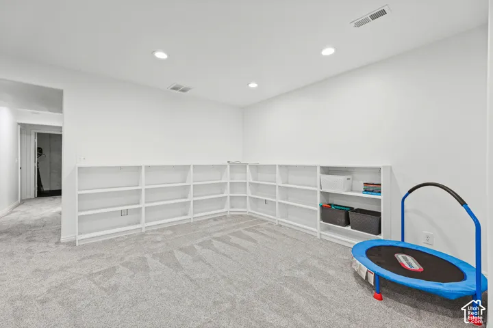 Gray carpeted room featuring recessed lighting and built-in white shelving