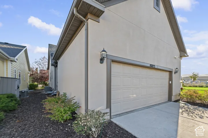 Stucco exterior with a paneled garage door, integrated exterior lighting, and a concrete driveway