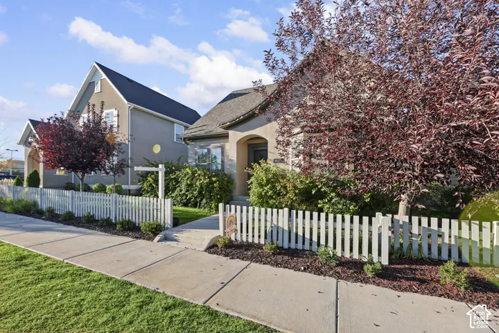Stucco exterior with an arched entryway, gabled roofline, and a white picket fence
