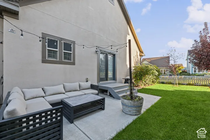 Exterior patio with concrete slab, double glass-paneled entry doors, and a wood picket fence enclosing a grassy yard