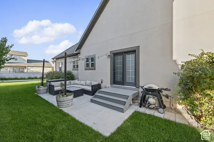 Expansive concrete patio with integrated steps, direct access via double doors, and a surrounding manicured lawn