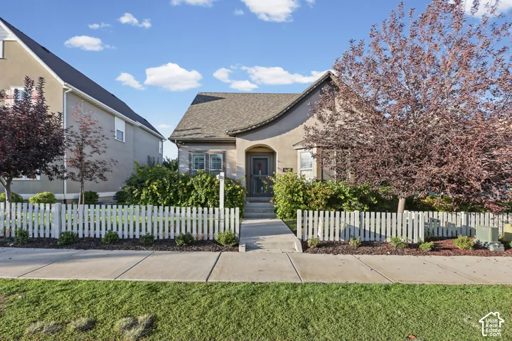 Stucco exterior with an arched entryway, gabled roof, and a white picket fence