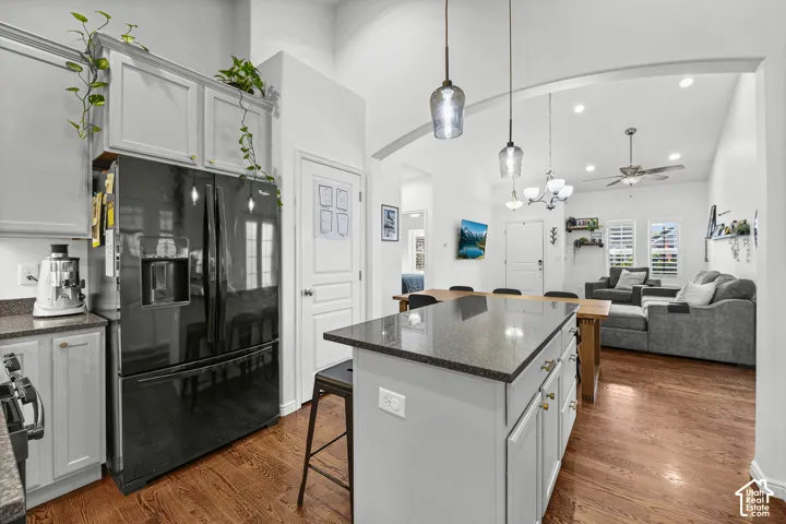 Kitchen featuring a black French door refrigerator, light gray cabinetry with gold-finish hardware, dark speckled countertops, and pendant lighting