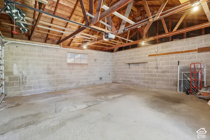 Exposed wood rafter ceiling, concrete block walls, concrete flooring, and a single window
