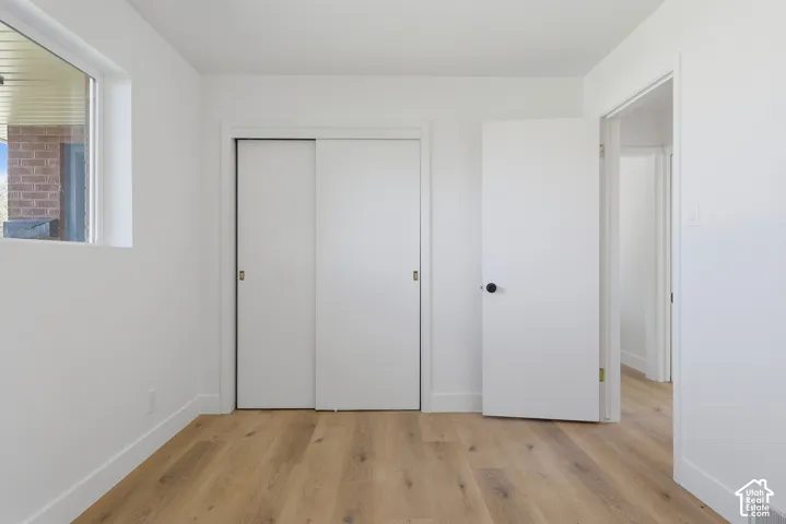 Recessed window, wood-finish flooring, white walls, and a sliding door closet