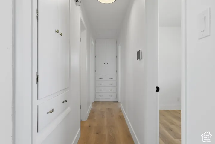 Hallway featuring wood-finish flooring, built-in cabinetry, and modern wall-mounted light fixtures