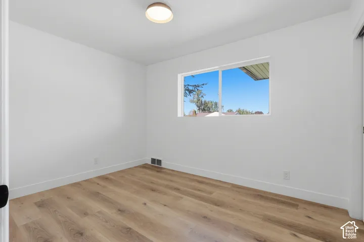 White walls, wood-finish flooring, and a flush-mount ceiling light
