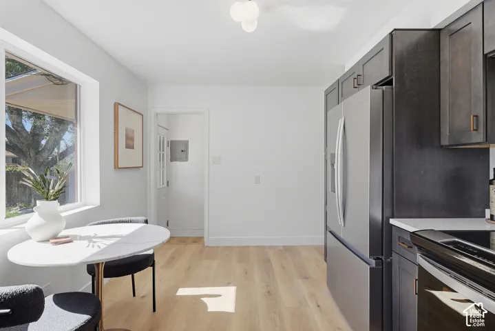 Modern kitchen featuring dark wood-finish cabinetry, stainless steel refrigerator, white countertops, and wood-finish flooring