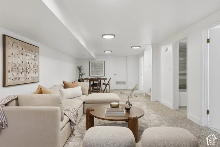 Recessed lighting illuminates the carpeted floor, white walls, and built-in ceiling features