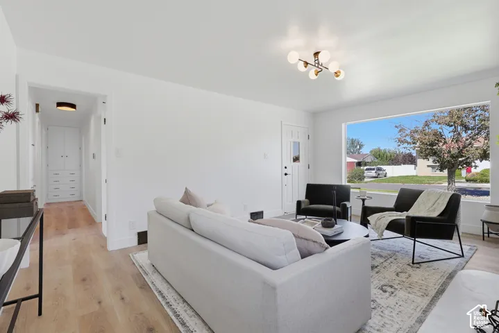 Bright living area featuring wood-finish flooring, a large picture window, and a contemporary ceiling light fixture