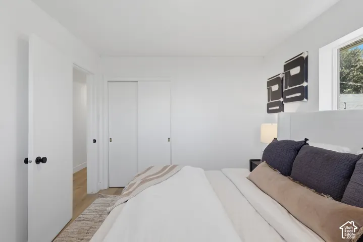 White painted walls with wood-finish flooring, featuring a window and white solid core doors