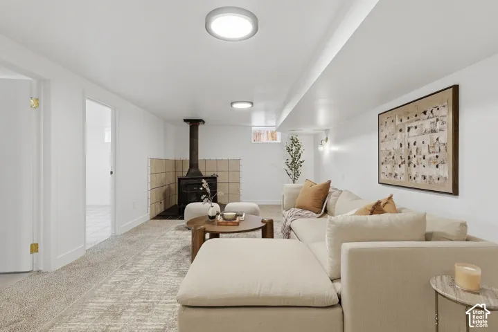 Recessed ceiling lighting, wood-burning stove, tile hearth, light-toned carpeting, and a built-in wall sconce