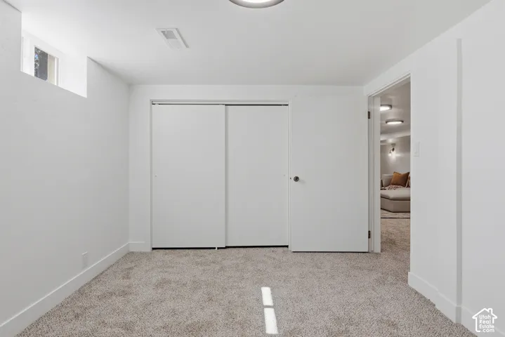 Light-toned carpeting, white walls, and a built-in closet with sliding doors