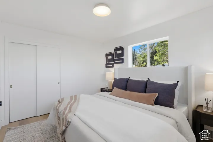 White walls, wood-finish flooring, and a window with exterior tree scenery