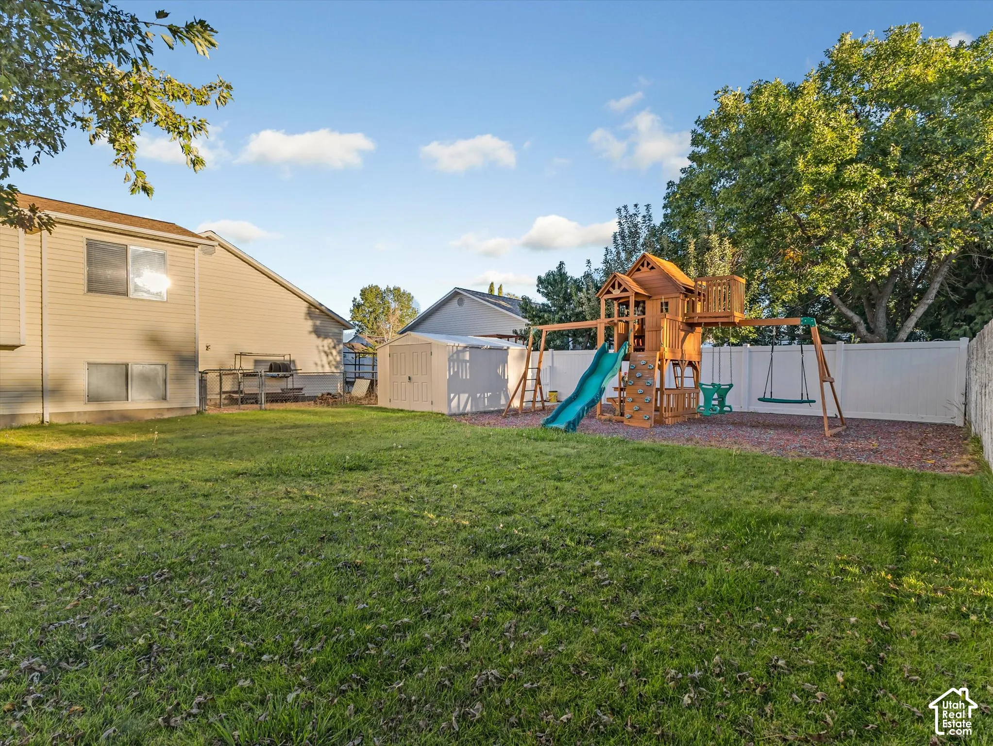 Expansive lawn area with a white privacy fence and a dedicated play structure