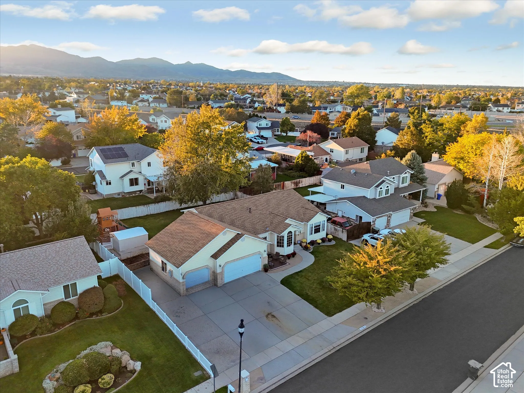 Expansive neighborhood setting with mature landscaping, paved streets, and mountain backdrop
