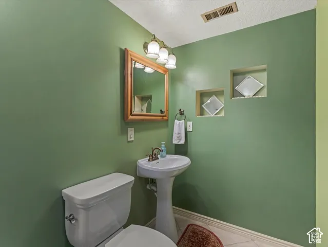Pedestal sink with a white basin, wood-framed mirror, and recessed wall shelving