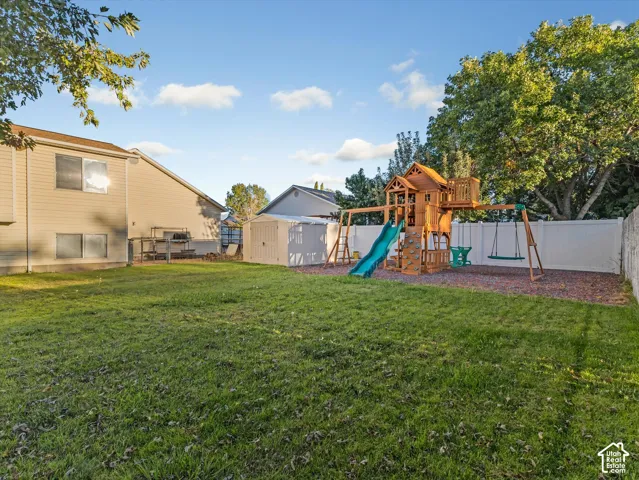 Expansive lawn area with a white privacy fence and a dedicated play structure