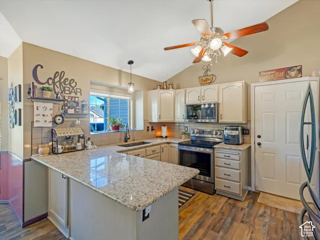 Kitchen featuring wood-finish flooring, light-toned cabinetry, stainless steel appliances, and a vaulted ceiling with a ceiling fan