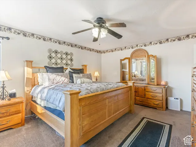 Carpeted flooring, ceiling fan, and window with curtain rod