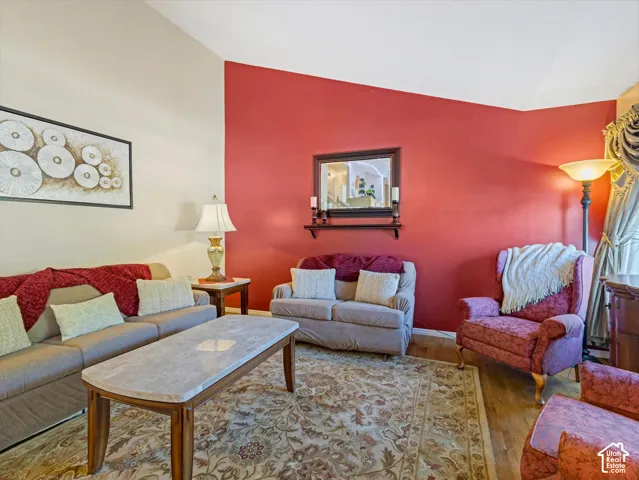 Vaulted ceiling with angled wall, wood-finish flooring, and a decorative wall mirror